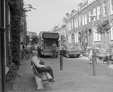 884243 Afbeelding van een oudere bewoner van de Kwartelstraat te Utrecht, op een openbare bank in de straat, met ...